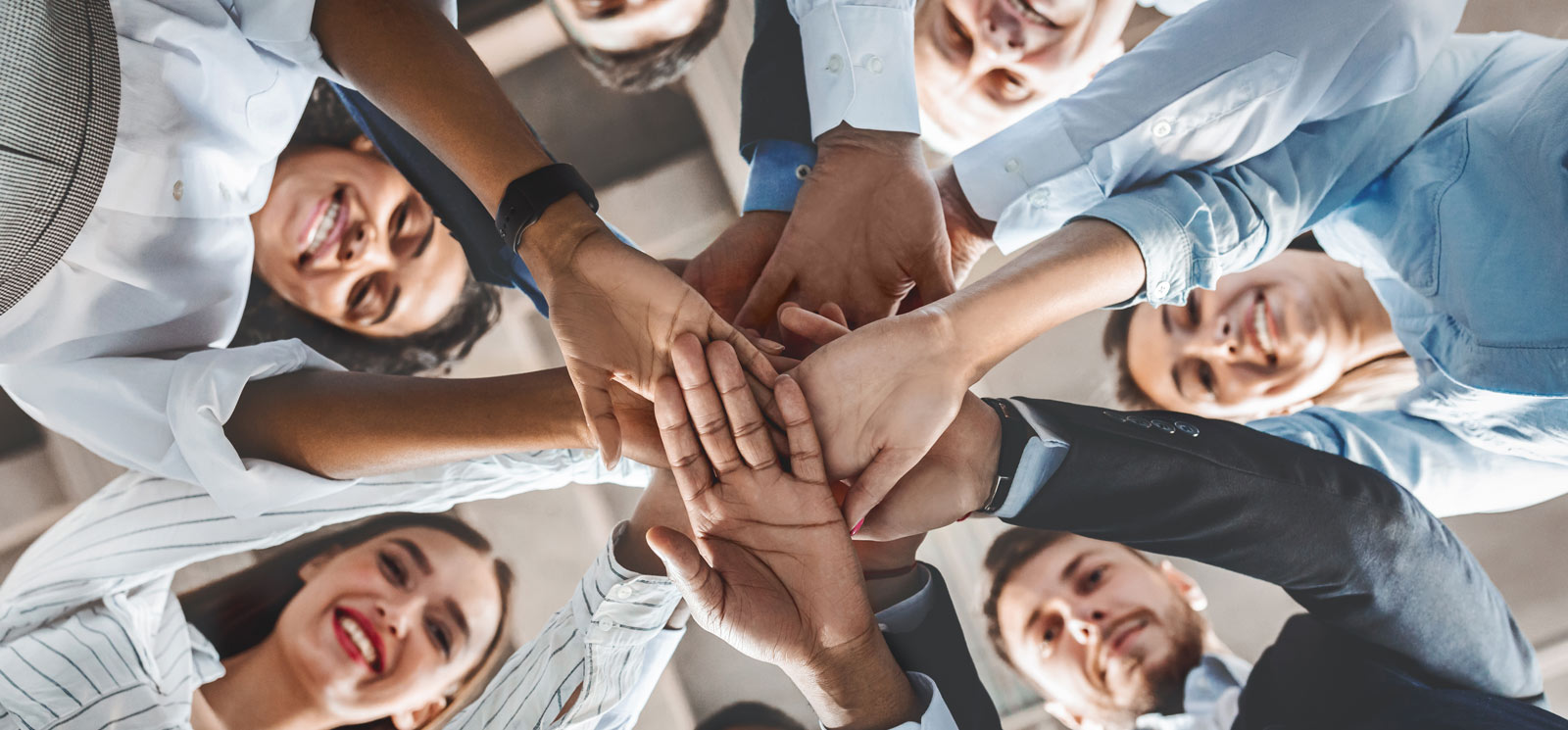 happy co-workers with stacked hands