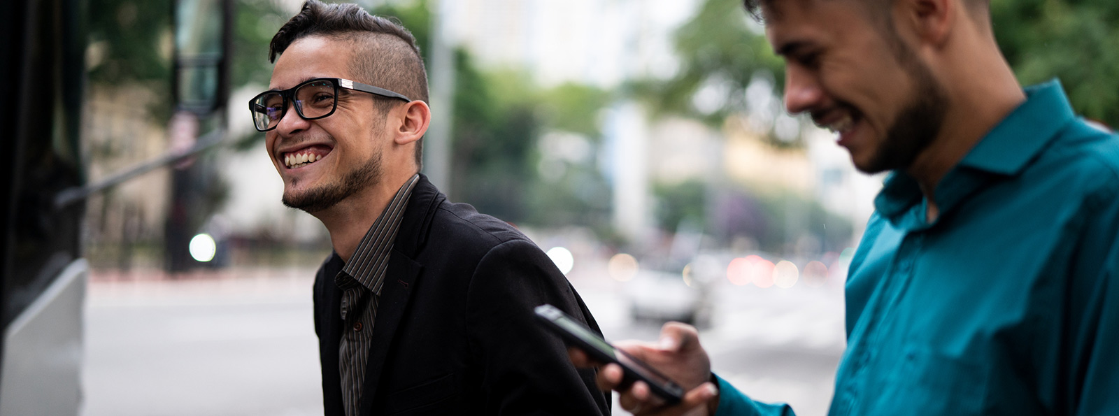 Two male friends walking holding phones.